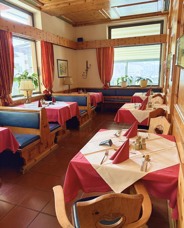 Innenansicht eines hellen Restaurants mit Holztischen und Stühlen.